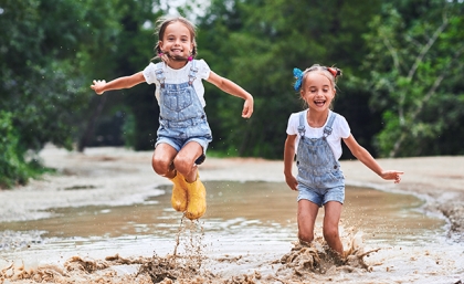 Twin girls jumping and playing in a creek