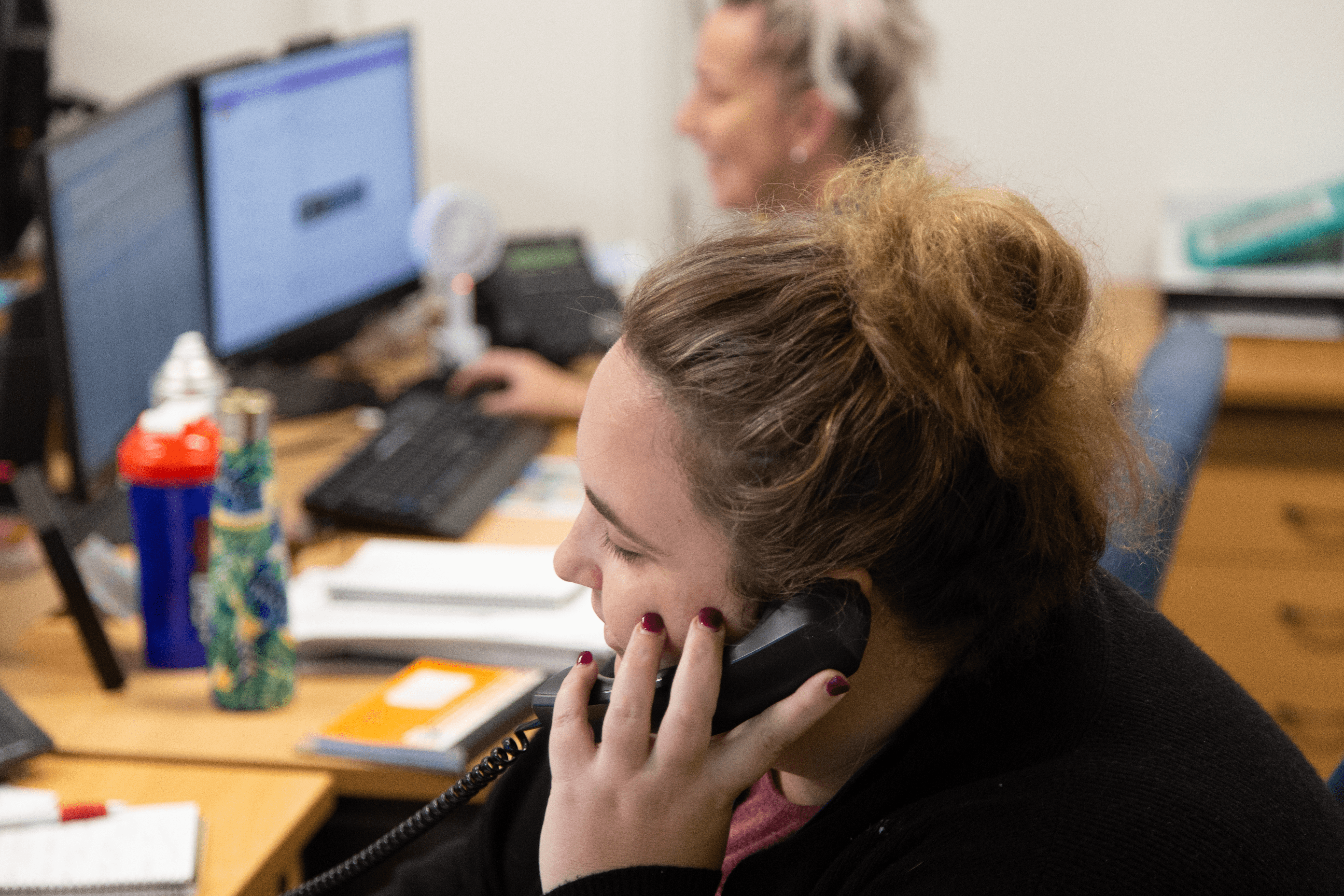 Woman sitting at office desk speaking on phone