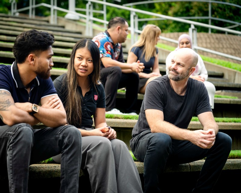 People sitting and talking on tiered grass seating in a park